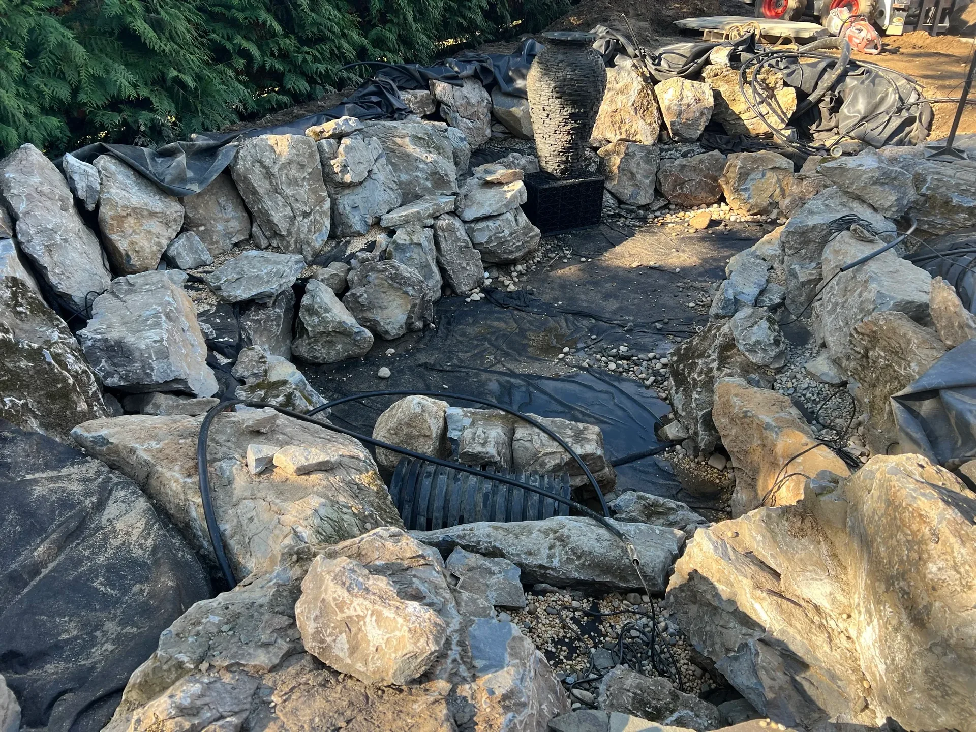 Russo Multi-Feature Water Garden in Rockville Centre, NY during construction, with boulders, liner, and plumbing in place
