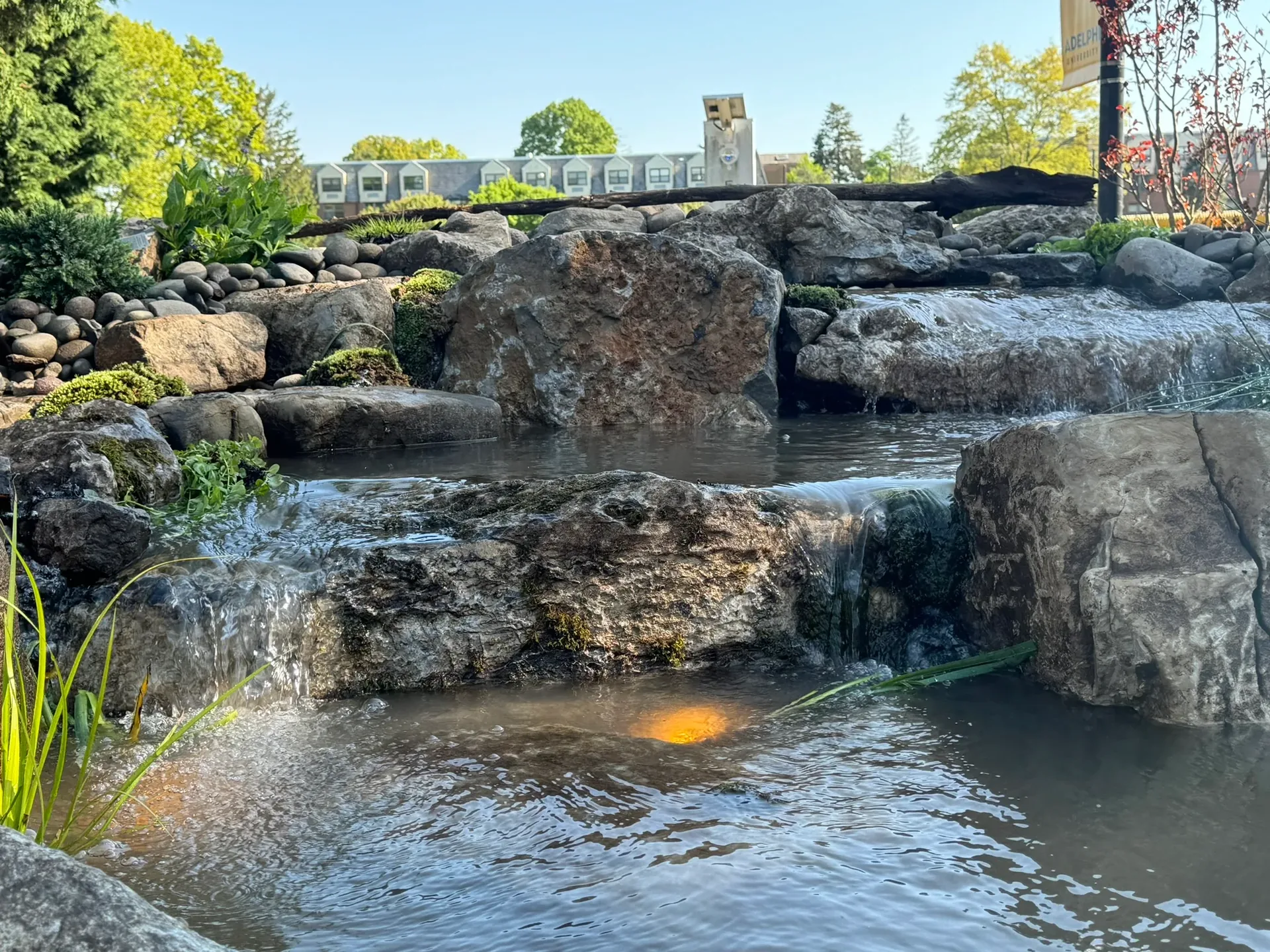 Adelphi University Waterfall in Garden City, NY after construction, with water flowing over hand-placed boulders